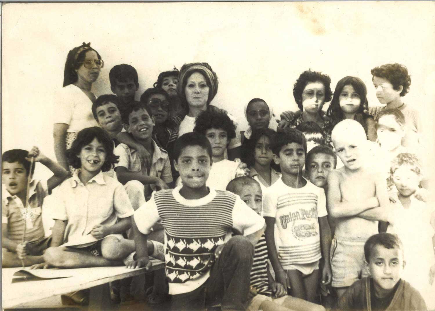 Toni Maraini (au centre) avec des enfants participant à l’atelier d’art gratuit, Moussem d’Assilah, 1979. Photo : M. Melehi, archives T. M.
